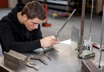 Apprentice with metal workpiece in the vocational school
