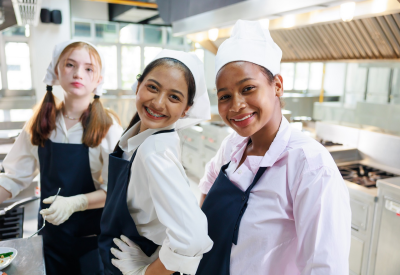 Group portrait of young woman cooking student. Cooking class. Culinary classroom. Group of happy young woman multi-ethnic students are focusing on cooking lessons in a cooking school
