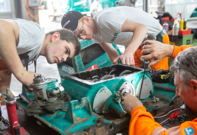 Tripartite vocational training conference: apprentices and trainers work on one engine
