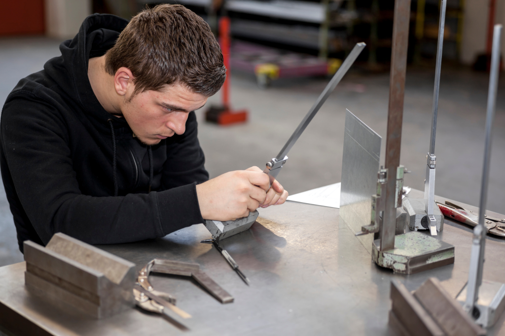 Apprentice with metal workpiece in the vocational school